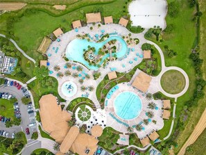 Vue aérienne d’un complexe hôtelier doté de plusieurs piscines, d’un terrain de golf et d’un parking.