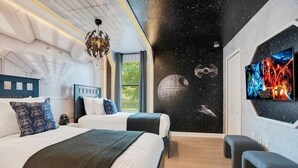 Une chambre avec deux lits, un mur décoré sur le thème de Star Wars et une affiche de film Star Wars.