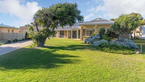 A residential property with a large lawn, a prominent tree, and a brick house with a metal roof.