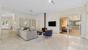 A spacious living room with a sofa, a coffee table, and a TV. There is a sliding glass door leading to an outdoor area.