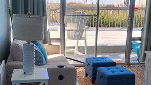 A modern living room with a large sliding glass door leading to an outdoor deck. - Oceanfront Condo*Walkout Patio Beach Access*Steps to the Sea* (North Myrtle Beach)