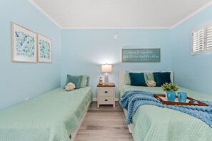 A bedroom with two single beds, a nightstand with a lamp, a wall quote, and a window with shutters. - Oceanfront Condo*Walkout Patio Beach Access*Steps to the Sea* (North Myrtle Beach)