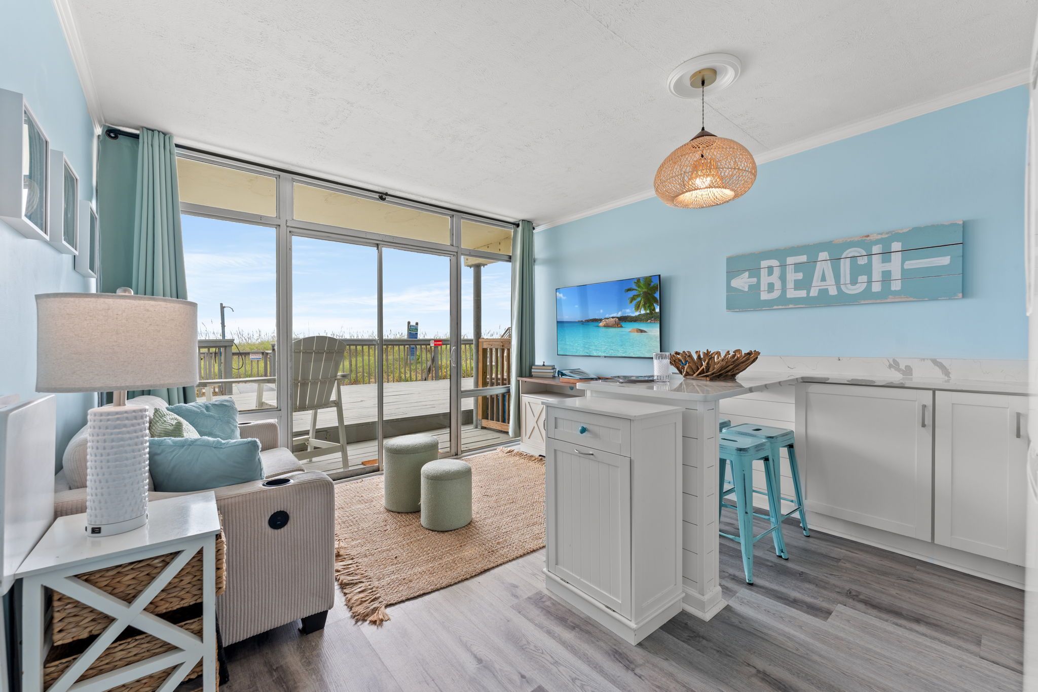 Une cuisine moderne dotée d’un grand îlot central, d’un coin repas offrant une vue agréable et d’une décoration sur le thème de la plage.