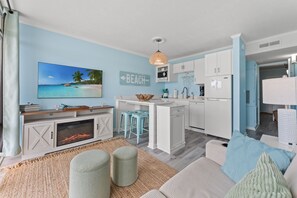A modern kitchen with white cabinets, a central island, and blue bar stools. - Oceanfront Condo*Walkout Patio Beach Access*Steps to the Sea* (North Myrtle Beach)