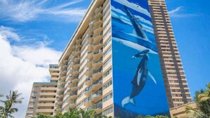A high-rise hotel with a distinctive exterior featuring a large mural of a whale and ocean waves. - Central Waikiki  Bch Gear, Parking, Kitchen, King (Honolulu)