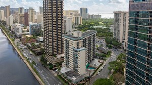 A high-rise building complex with multiple floors, a central courtyard, and a waterfront view. - Central Waikiki  Bch Gear, Parking, Kitchen, King (Honolulu)