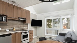 A modern kitchen with wooden cabinets, a built-in microwave, and a large window overlooking a deck.
