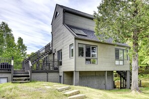 Una casa moderna de dos pisos con una escalera destacada, ventanas grandes y un garaje.