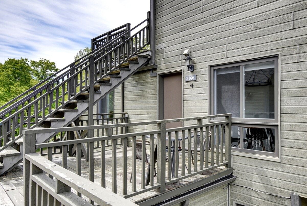 A residential building with a wooden deck, a staircase, and a door marked with the number 2166.