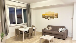 Ein Wohnzimmer mit Esstisch, zwei Stühlen, einer Couch und einem Couchtisch.