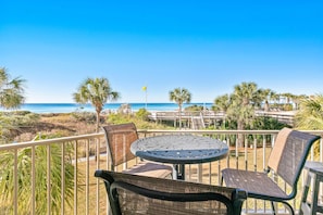 Ein Balkon mit Tisch und Stühlen mit Blick auf einen Strand und Palmen.