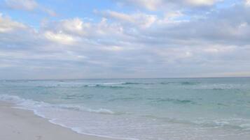Een strand met een breed zandstrand en rustige golven.
