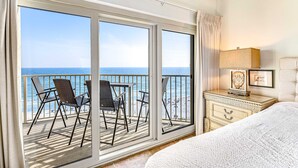 Et soveværelse med balkon, seng, natbord og havudsigt.
