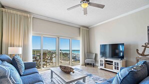 Un salon avec un canapé, une table basse, un téléviseur et un balcon offrant une vue agréable.