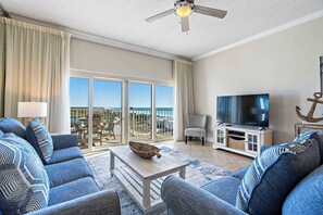 A living room with a sofa, a coffee table, a TV, and a balcony with a view. - Gulf views from private balconies, beach access (Miramar Beach)