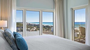 Une chambre d’hôtel avec un grand lit, une vue sur l’océan et un balcon équipé d’une chaise.