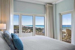 A hotel room with a large bed, a view of the ocean, and a balcony with a chair. - Gulf views from private balconies, beach access (Miramar Beach)