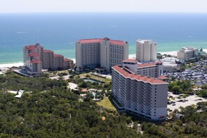 Ein Hotelkomplex an der Küste mit mehreren Hochhäusern, einem Parkplatz und Blick auf den Strand.