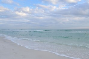 Ein Strand mit Wellen, blauem Himmel und ruhiger See.