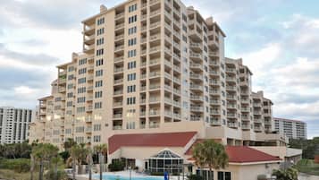 A multi-story hotel with a pool area and a beach view.
