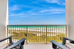 A balcony with a view of a beach, featuring a railing and two chairs. - Exclusive beachfront condo w/private balcony (Miramar Beach)