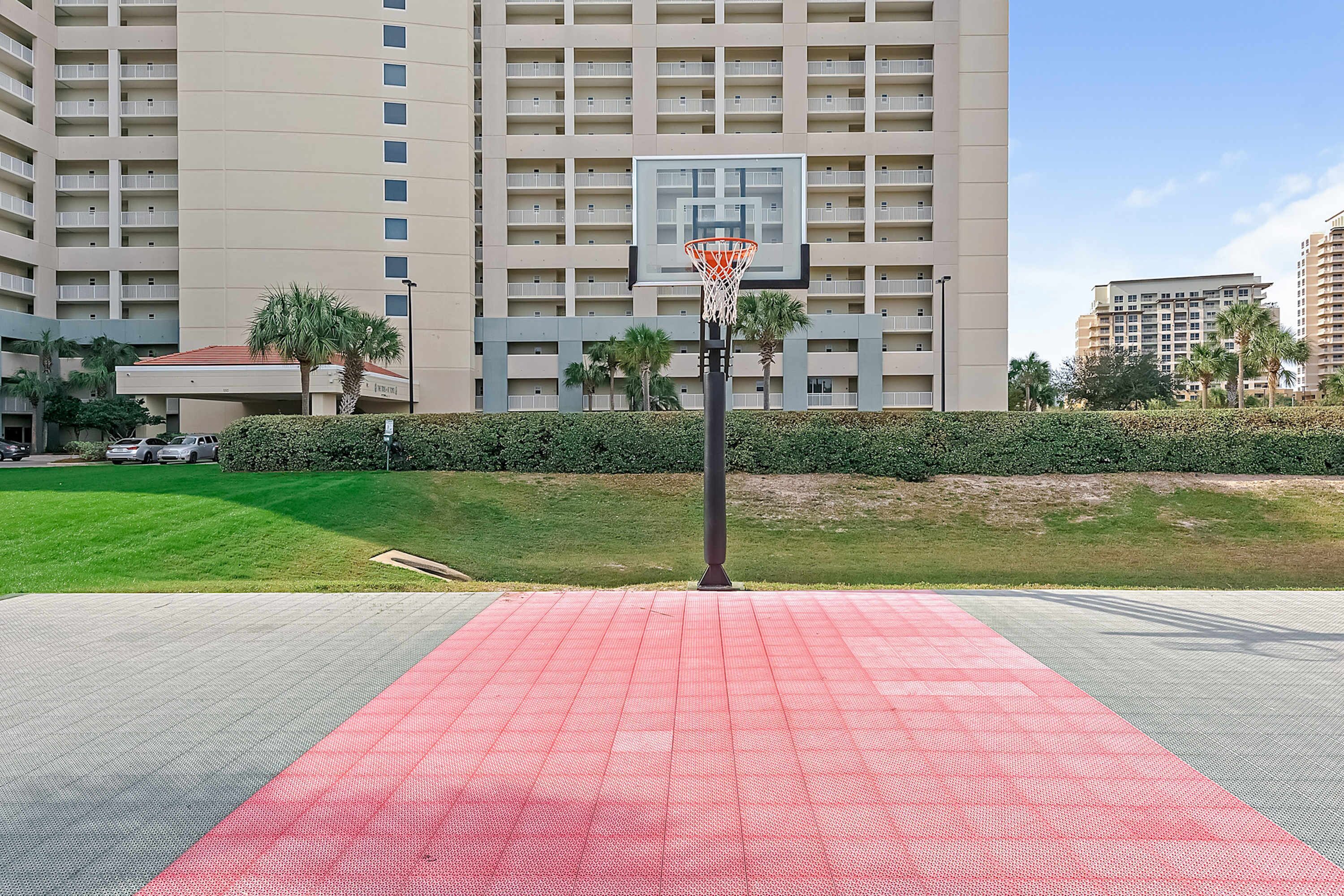 Una pista de bàsquet amb un cèrcol davant d'un edifici alt.