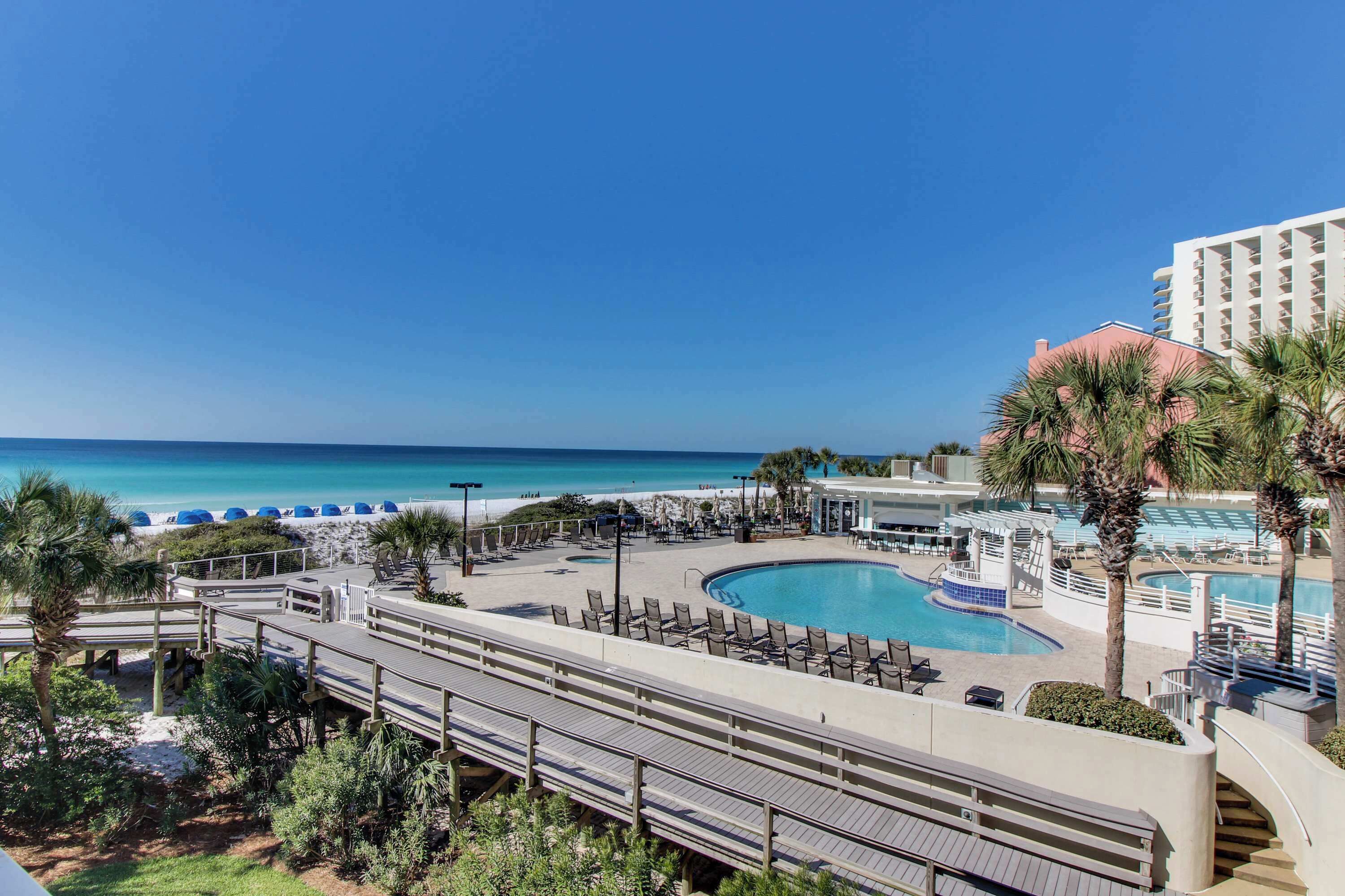 A resort with a pool, beach, and palm trees.