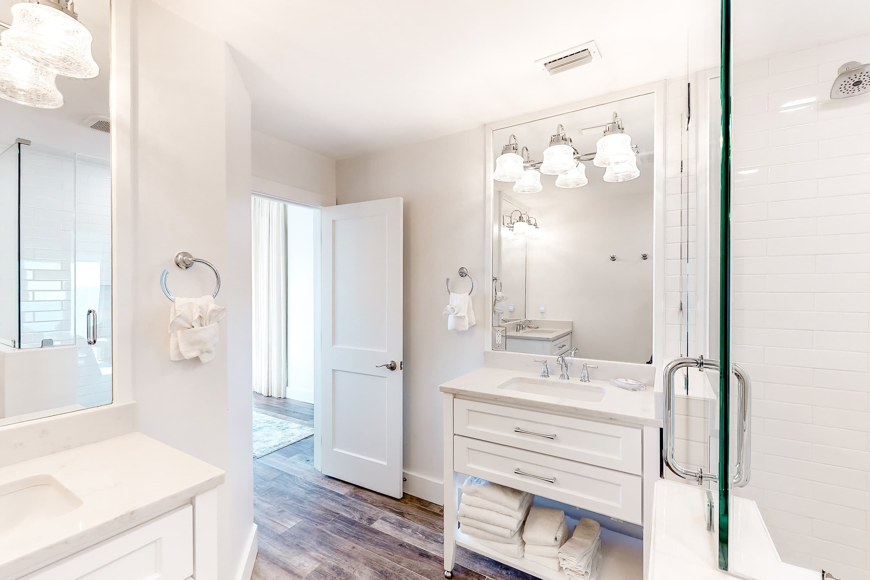 A modern bathroom with a large mirror, white fixtures, and a glass shower enclosure.