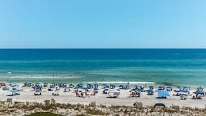 Uma praia com vários guarda-sóis e cadeiras de praia, indicando uma área de hospedagem à beira-mar.