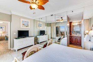 Ein Hotelzimmer mit Bett, Fernseher, Schminktisch und Spiegel, mit Blick nach draußen.