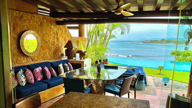 A modern living room with a glass table, blue sofa, and a view of the ocean. - Exclusive Manzanillo Bay Residencias 1-bdrm, seaside condo in charming Troncones (Troncones)