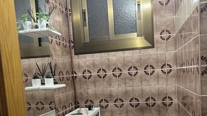Un baño con inodoro, lavamanos y ventana sobre el espejo.