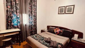 Un dormitorio con cama, escritorio, silla, mesita de noche y lámpara de pared.