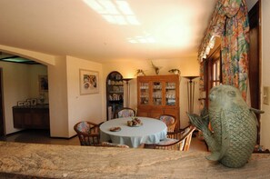 A dining area with a round table, chairs, a fish sculpture, a cabinet with glass doors, and a painting on the wall.