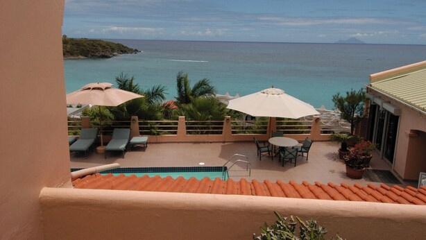 A terrace with lounge chairs and umbrellas overlooking a pool and the sea. - 5BR Villa, Pool & Little Bay Views (Little bay)