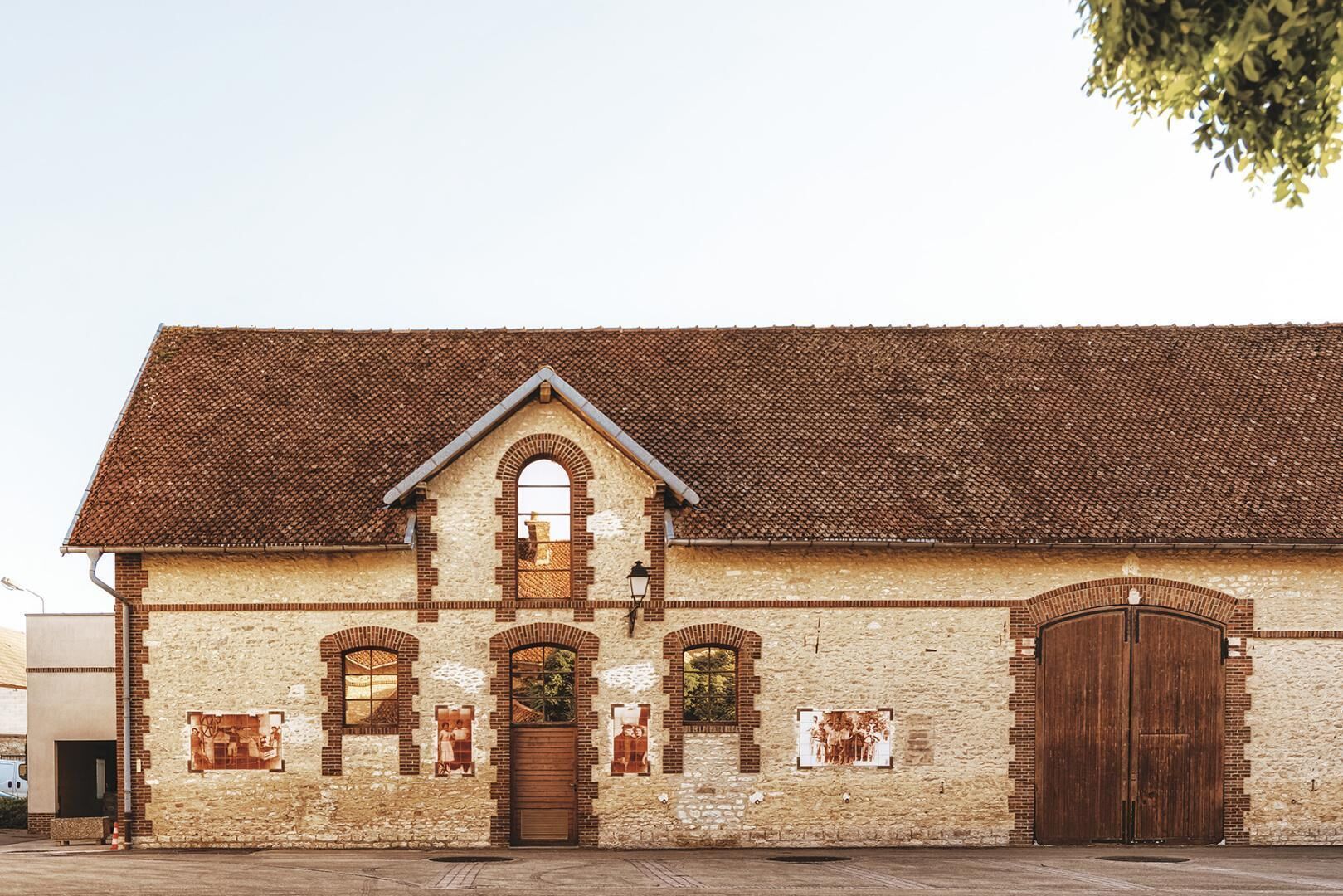 A building with a tiled roof, arched windows, and a large wooden door.