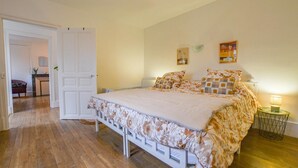 Een slaapkamer met een bed, een bedlamp en een deur naar een andere kamer.