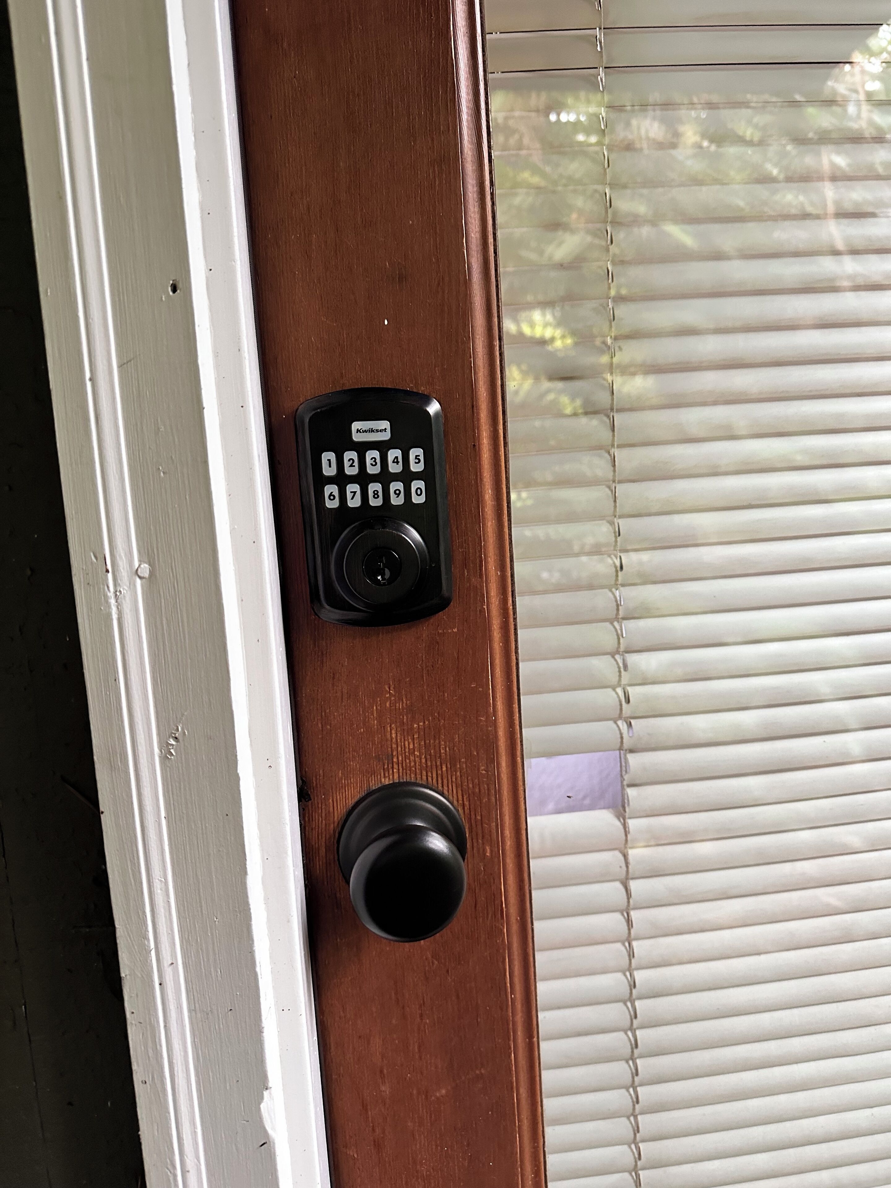 Une porte dotée d’une serrure à clavier Kwikset et d’une poignée de porte ronde.