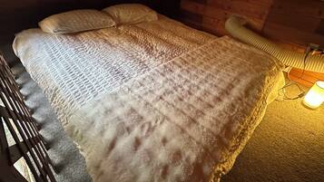Un letto con una coperta e cuscini testurizzati, una testiera in legno e una lampada sul comodino.