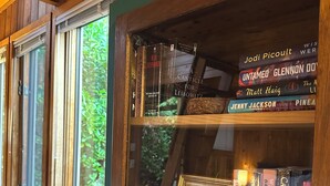 A wooden bookshelf with books and a framed quote.