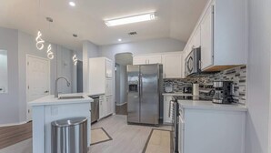 A modern kitchen with white cabinetry, stainless steel appliances, and a central island. - Luxury Harker Hideaway Relax, Unwind, Ex (Harker Heights)