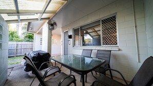 A covered patio with a glass table and chairs, a ceiling fan, and a view of the backyard. - Comfy Kirwan Getaway (Kirwan)