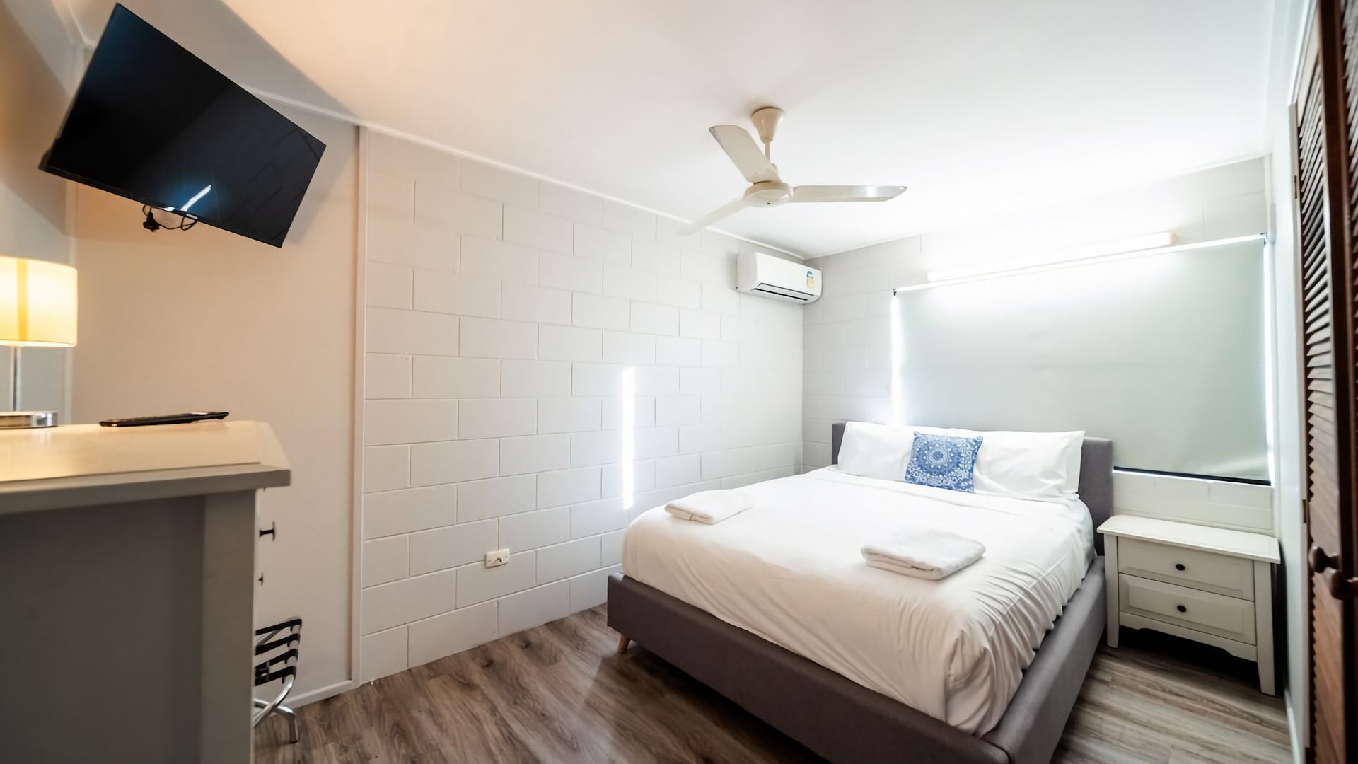 Ett hotellrum med en säng, ett nattduksbord, en tv och en takfläkt.