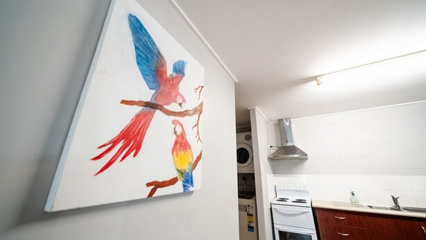 A kitchen with white cabinets, a stove, and a wall-mounted exhaust hood. - Comfy Kirwan Getaway (Kirwan)