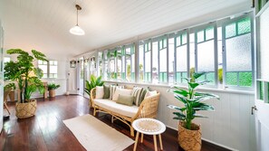 A room with a wicker sofa, a small round table, and potted plants. - Tropical getaway 10 min to city Vacation Home in Hermit Park (Hermit Park)
