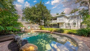 Uma propriedade residencial com piscina, quintal cercado e uma casa de dois andares com varanda.