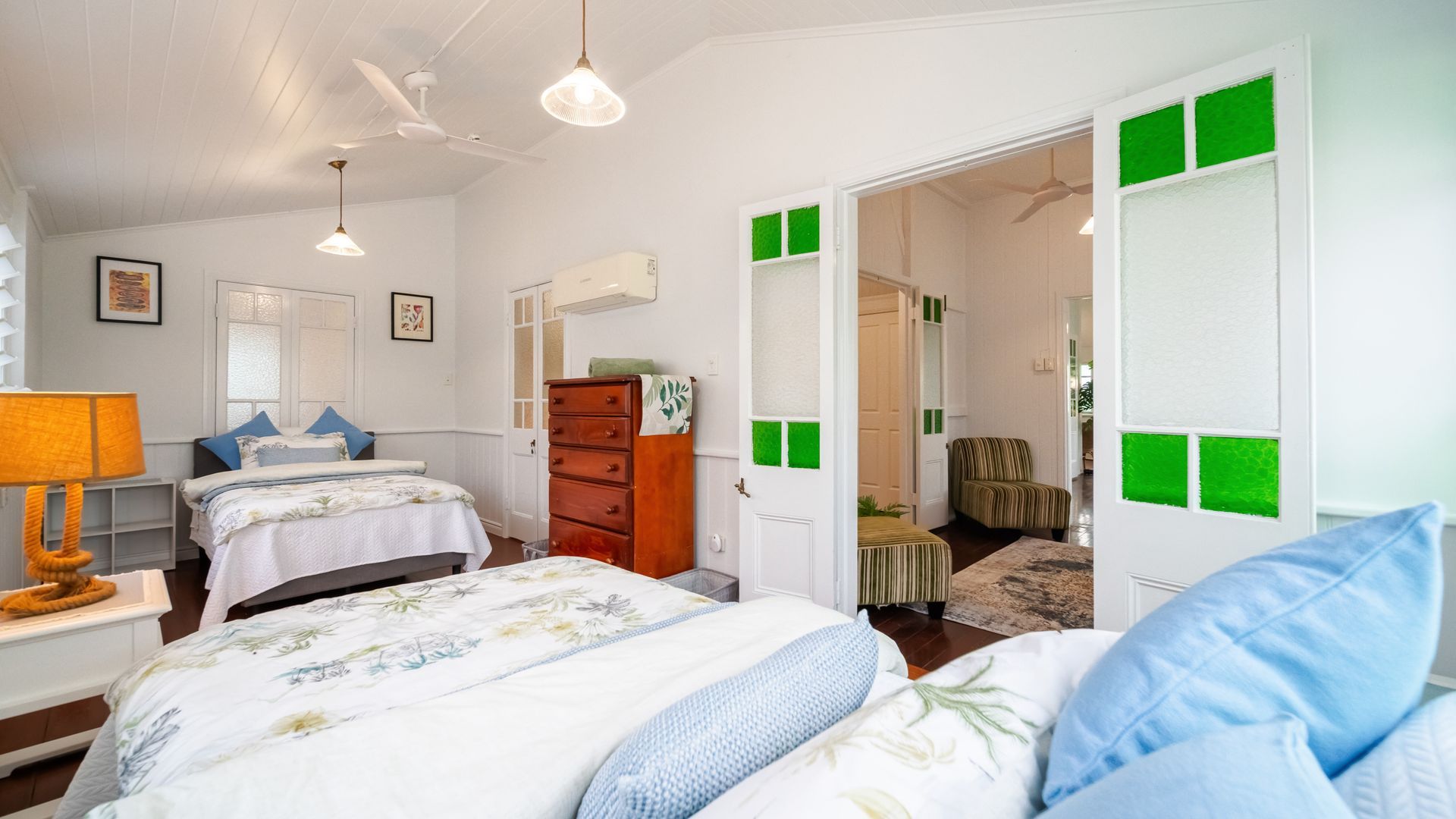 A room with two beds, a dresser, a chair, and a door leading to another room.