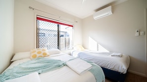 Une chambre d’hôtel avec deux lits, une fenêtre donnant sur un beau paysage, un climatiseur et un thermostat fixé au mur.