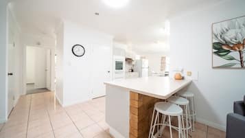 A modern kitchen with a central island, white cabinetry, and a clock on the wall.