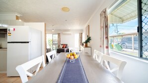 Een moderne keuken met een inbouwkoelkast, een eethoek met een tafel voor twee personen en een groot raam met uitzicht op de omgeving.